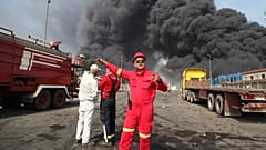 Firefighters work as black smoke rises in the sky after a massive explosion rocked a port near the southern city of Bandar Abbas, 26 April 2025