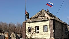 Ein russischer Soldat hisst eine Flagge auf dem Dach eines Hauses in der Nähe der russischen Region Kursk, nachdem russische Truppen das Gebiet zurückerobert haben.