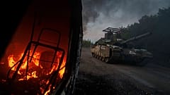 Un char ukrainien passe à côté d'une voiture en feu près de la frontière russo-ukrainienne dans la région de Soumy en Ukraine, le 14 août 2024.