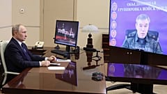 Российский солдат поднимает флаг на крыше дома в районе Курской области России после возвращения территории российскими войсками.