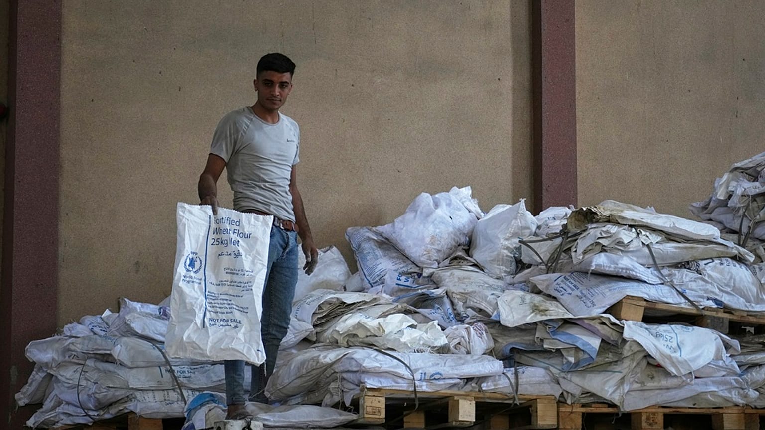 عامل فلسطيني يحمل أحد أكياس الطحين الفارغة في مستودع برنامج الأغذية العالمي في مخيم النصيرات للاجئين ، قطاع غزة ، السبت 26 أبريل / نيسان 2025.