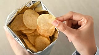 Une personne sort une chips du sac.