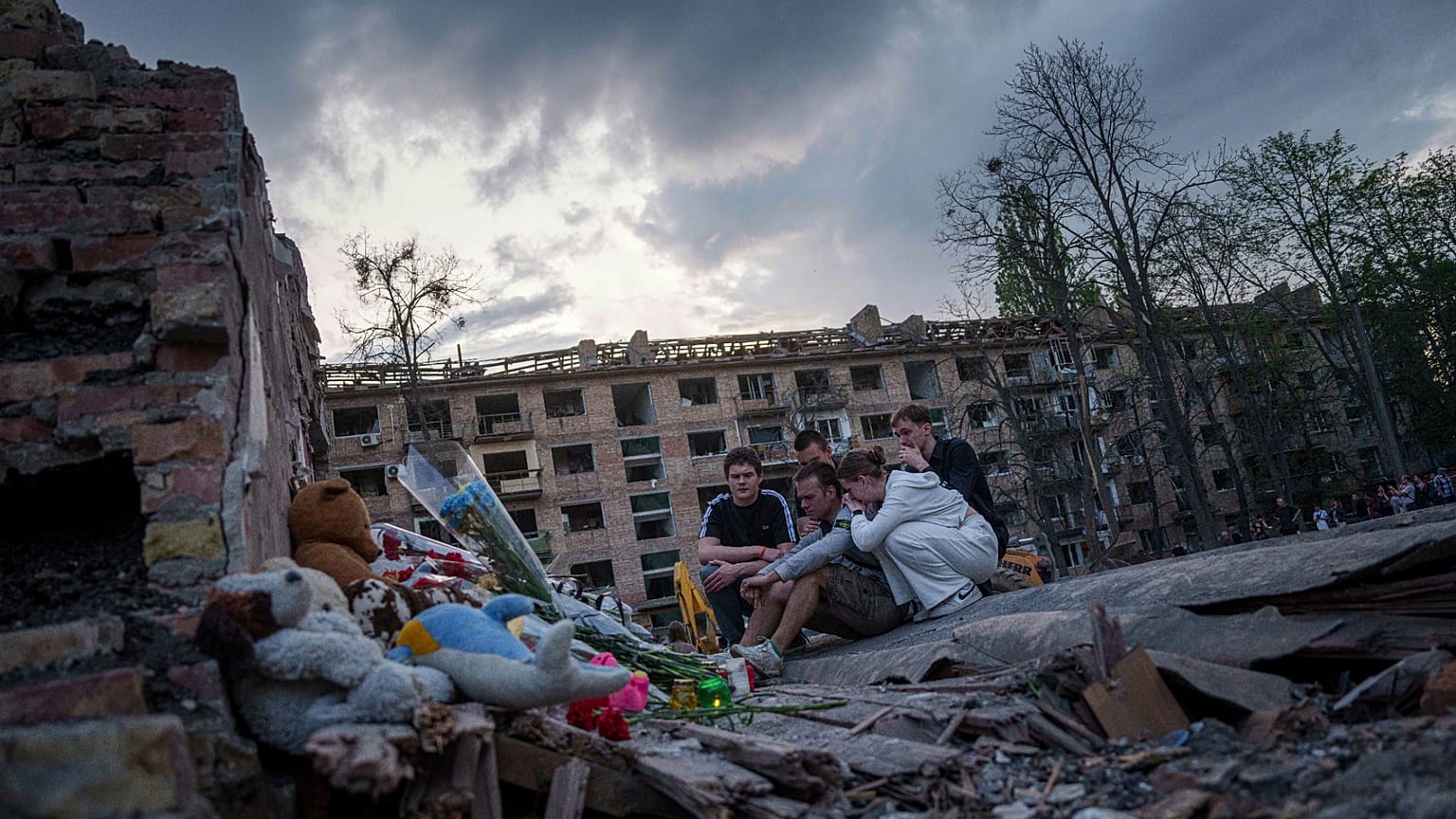 Amigos de un adolescente ucraniano muerto en un ataque ruso se reúnen junto a los restos de una casa en Kiev, 25 de abril de 2025.