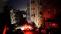 Ein Auto fährt während eines landesweiten Stromausfalls am Montagabend, 28. April 2025, eine unbeleuchtete Straße in Lissabon entlang.