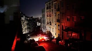 Ein Auto fährt während eines landesweiten Stromausfalls in der Nacht zum Montag, den 28. April 2025, eine unbeleuchtete Straße in Lissabon entlang.