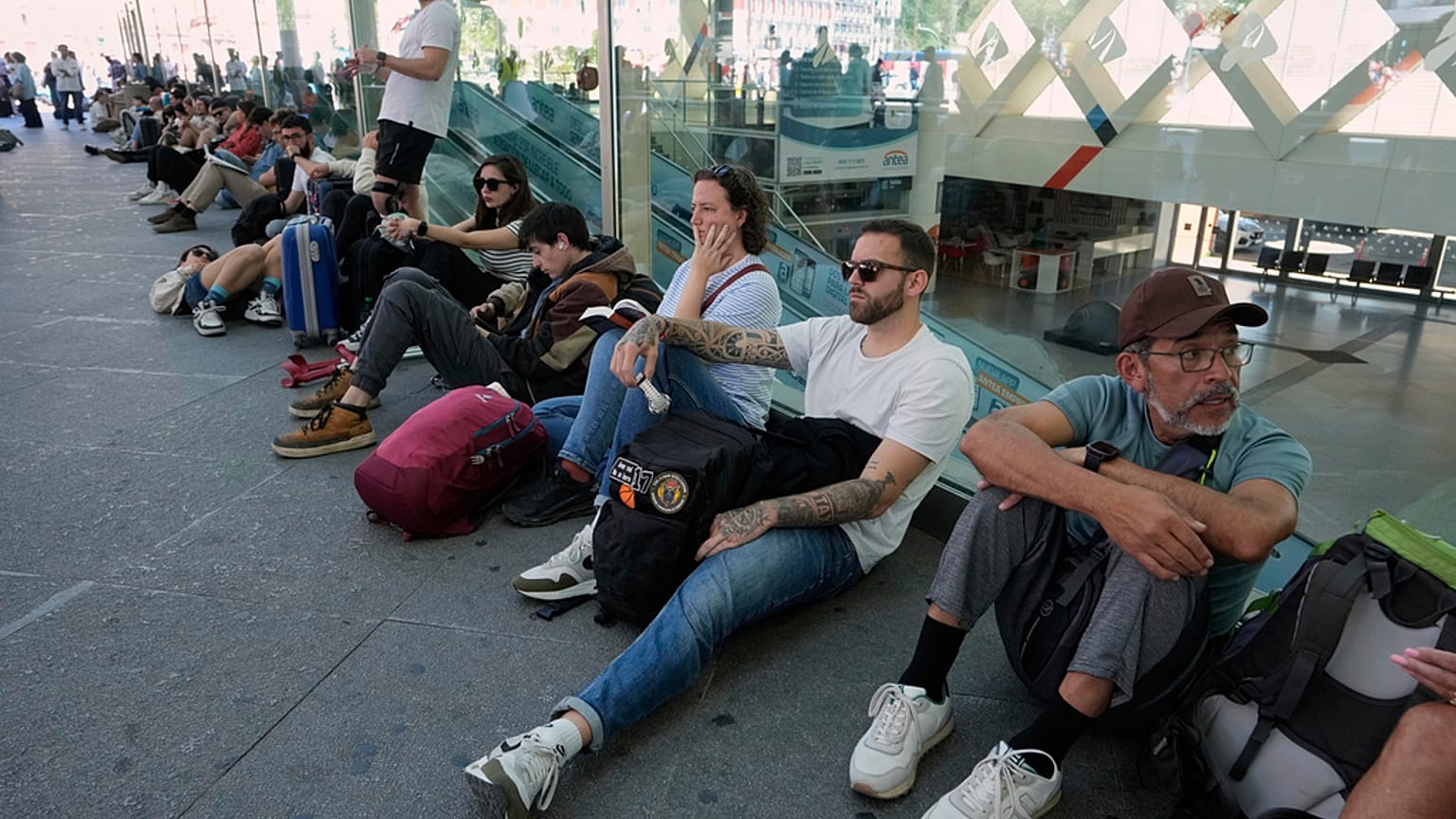 Viajeros esperan en Atocha ante la imposibilidad de subir a un tren debido al apagón. 