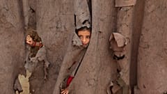 Ein afghanisches Flüchtlingsmädchen blickt durch einen zerrissenen Vorhang am Eingang ihres Zuhauses im Kababayan-Flüchtlingslager in Peshawar, Pakistan, am 8. April 2025