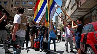 صبية درزيون يحملون أعلامهم الدينية بجانب مسلحين درزيين ، بعد يوم من الاشتباكات بين أفراد من الطائفة الدرزية ومقاتلين موالين للحكومة 29 أبريل 2025