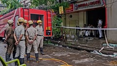 Feuerwehrleute stehen bereit, während Polizisten den Eingang eines Hotelgebäudes bewachen, das am Dienstag in Brand geriet und mehrere Todesopfer forderte, in Kolkata, Indien, Mittwoch, 30. April 2025