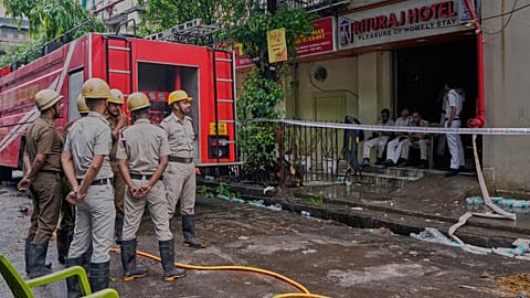 Des pompiers se tiennent devant l'entrée d'un hôtel en feu gardée par des policiers, qui a pris feu mardi causant plusieurs décès, à Kolkata, en Inde, mercredi 30 avril 2025.