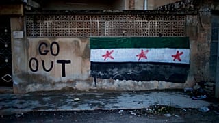  رسم جرافيتي يصور العلم السوري وشعار مكتوب عليه "اخرجوا 2012 في ادلب