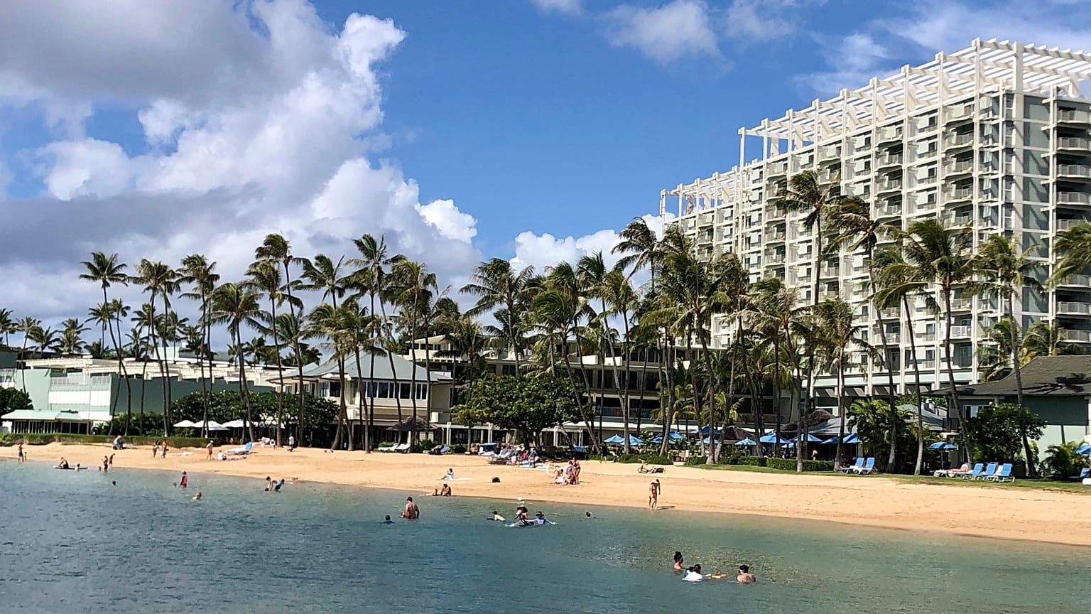 Se ve gente en la playa y en el agua frente al Kahala Hotel &amp; Resort de Honolulu.