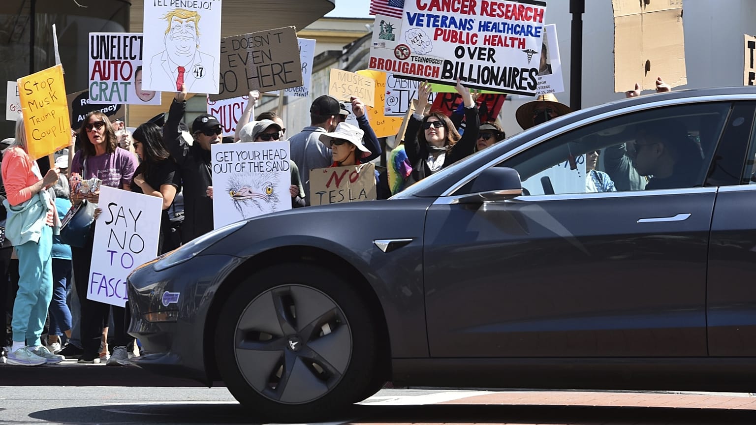 Tesla halad el egy Musk-ellenes tüntetés előtt Kaliforniában