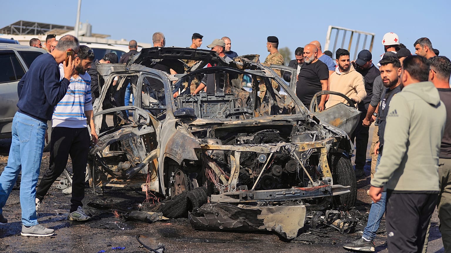 أشخاص يتجمعون قرب سيارة متفحمة أصيبت في غارة إسرائيلية في بلدة الغازية جنوب لبنان، الجمعة 18 أبريل/نيسان 2025