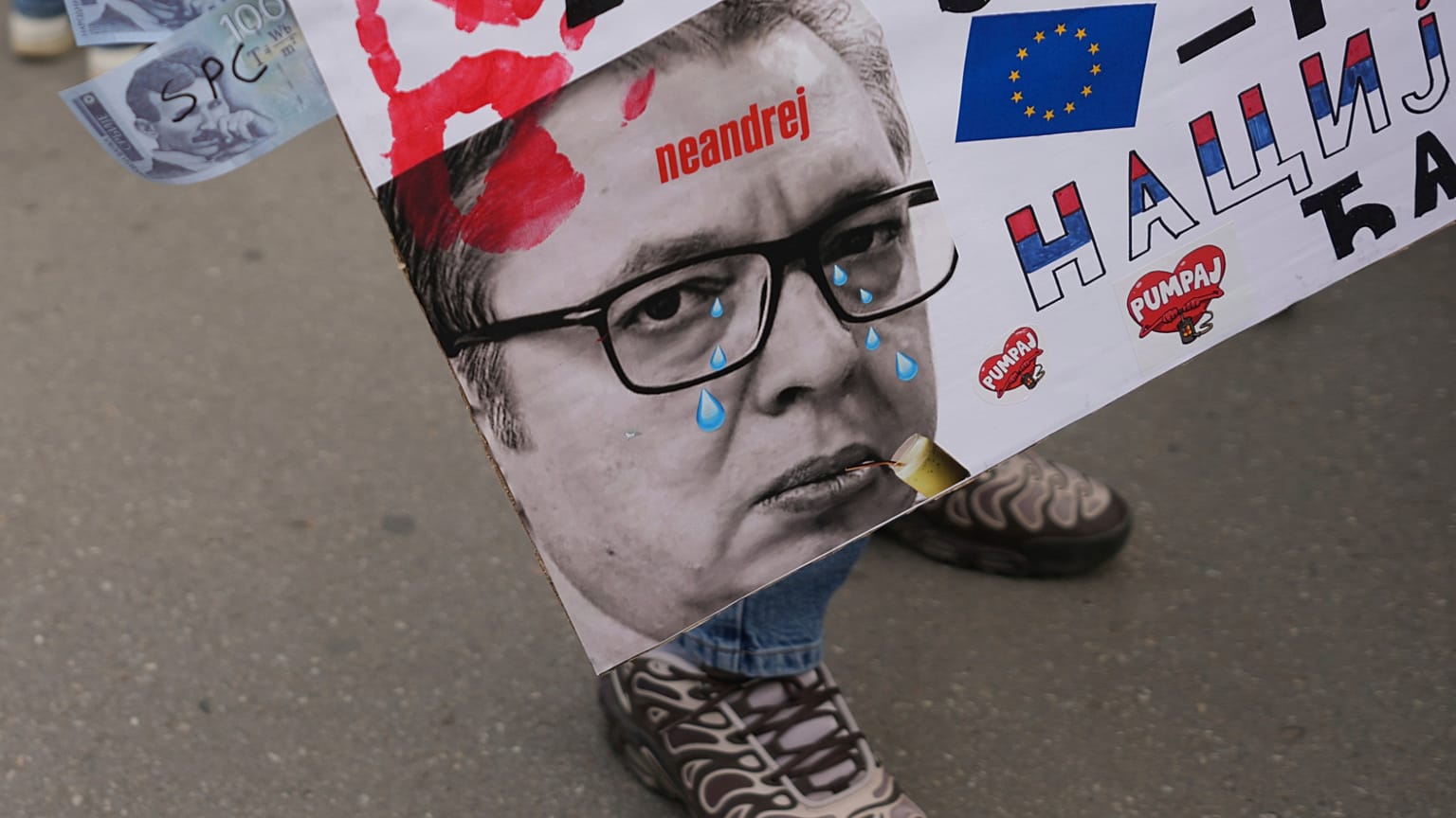 Egy nő plakátot tart, amelyen Aleksandar Vucic szerb elnök látható Újvidéken, Szerbia, 2025. április 25-én, pénteken.