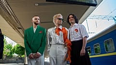 Die ukrainische Band Ziferblat steht unter der Infotafel «Eurovision Express», während sie am 01.05.2025 am Hauptbahnhof in Kiew, Ukraine, ankommt, um einen Zug zu nehmen