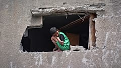 صبي ينظر إلى الفلسطينيين وهم يفتشون أنقاض منزل استهدفته غارة للجيش الإسرائيلي في قطاع غزة