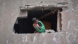صبي ينظر إلى الفلسطينيين وهم يفتشون أنقاض منزل استهدفته غارة للجيش الإسرائيلي في قطاع غزة
