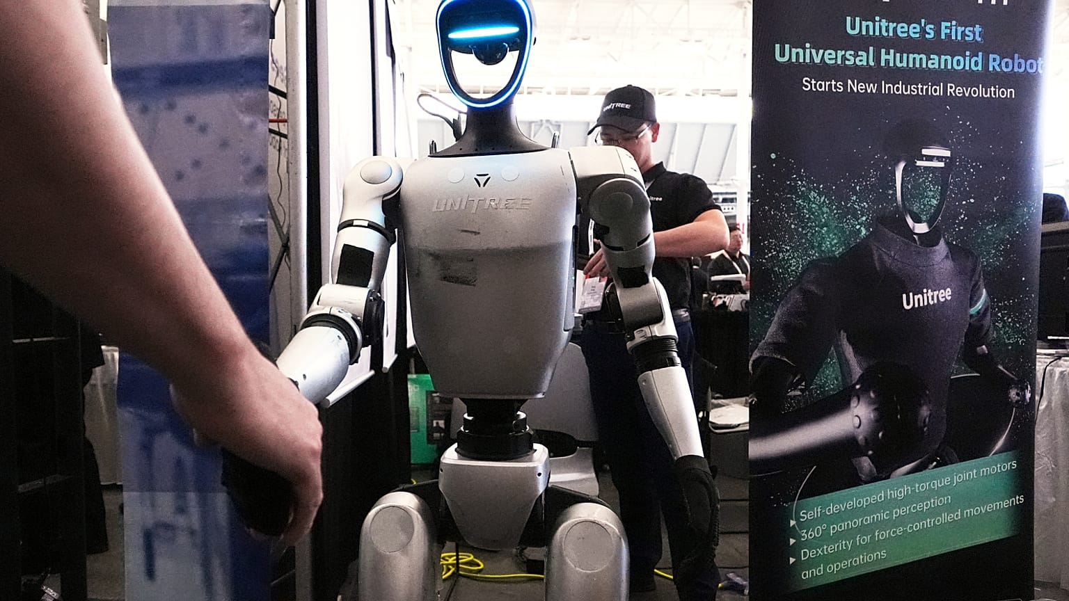 Bir Unitree robotu, 30 Nisan 2025 Çarşamba günü Boston'da düzenlenen Robotik Zirvesi ve Fuarı'nda bir konukla el sıkışıyor.