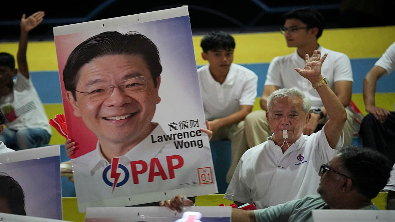 Seguidores del gobernante Partido de Acción Popular (PAP) sostienen una foto del primer ministro Lawrence Wong mientras esperan los resultados de las elecciones generales.
