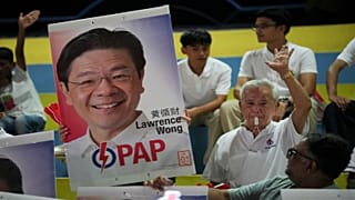 Halk Hareketi Partisi (PAP) destekçileri, genel seçim sonuçlarını beklerken ellerinde Başbakan Lawrence Wong'un resmini tutarak tezahürat yapıyor.