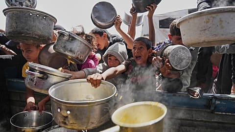 Palestinian children struggle to get donated food at a community kitchen in Khan Younis, Gaza Strip, Saturday, May 3, 2025.