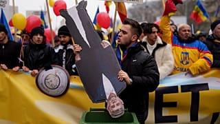 A man places cardboard cutouts of Romanian Prime Minister Marcel Ciolacu in a garbage container during a protest organised by AUR, in Bucharest, 1 March 2025