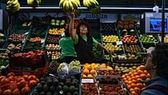 Una trabajadora alcanza un racimo de plátanos mientras un cliente espera, en Pamplona, ​​norte de España, el miércoles 15 de marzo de 2023.