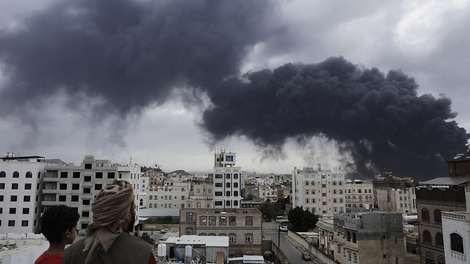 Yemenis watch as smoke billows following Israeli air strikes targeting Sanaa Airport, 6 May, 2025