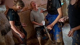 Una mujer reacciona entre lágrimas mientras es ayudada por voluntarios a limpiar el barro de su casa, que se vio severamente afectada por las inundaciones en Masanasa, Valenci