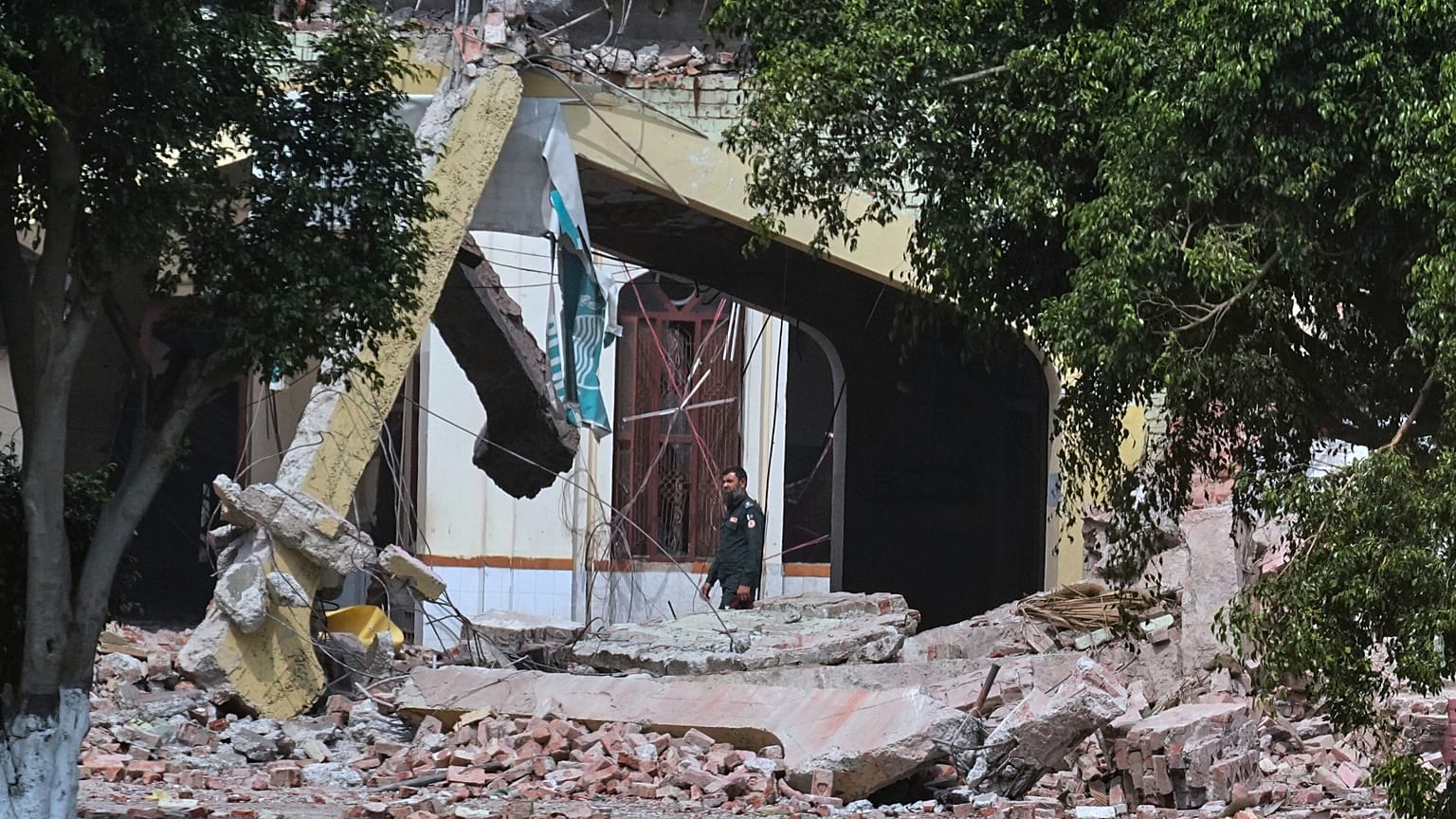 A security guard walks through rubble of a damaged building after a suspected Indian missile attack in Muridke, 7 May, 2025