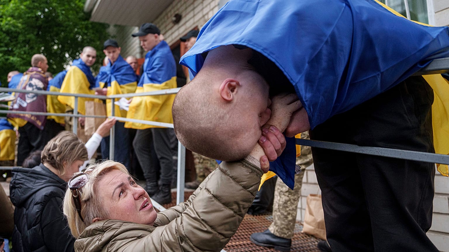 Egy ukrán katona kezet csókol egy nőnek, miután hazatért a fogságból az Oroszország és Ukrajna közötti hadifogolycsere során, 2025. május 6-án.