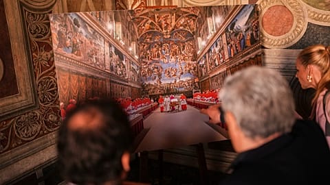 Journalists look at a photograph of the conclave where late Pope Francis was elected, 2 May, 2025