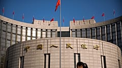 A woman walks past the headquarters of the People's Bank of China in Beijing, Friday, March 10, 2017. 