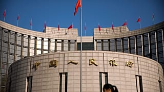 A woman walks past the headquarters of the People's Bank of China in Beijing, Friday, March 10, 2017. 