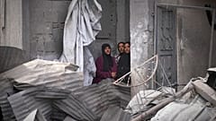 نساء فلسطينيات يراقبن عمليات البحث تحت أنقاض منزل في خان يونس استُهدف بغارة إسرائيلية أسفرت عن مقتل خمسة من عائلة أبو سحلول، 1 مايو 2025.