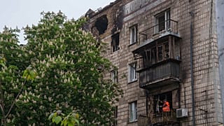 Um trabalhador municipal limpa os escombros de uma varanda de um edifício residencial danificado após uma greve russa em Kiev, a 7 de maio de 2025