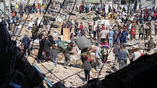 Palestinianos recolhem pertences de uma escola utilizada como abrigo por residentes deslocados que foi atingida duas vezes por ataques do exército israelita em Bureij, 7 de maio de 2025