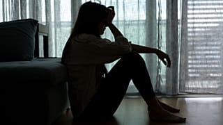 Una mujer angustiada se sienta en la oscuridad.