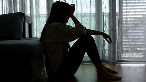 A distressed woman sits in the dark.