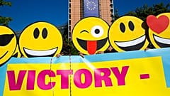 Mitglieder eines Flashmobs tragen Emoji-Masken, als sie am Dienstag, 30. August 2016, vor dem EU-Hauptquartier in Brüssel demonstrieren.