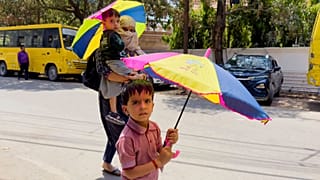 Μια γυναίκα και τα παιδιά της που επιστρέφουν από το σχολείο κρατούν ομπρέλες για προστασία από τον ήλιο στο βόρειο ινδικό κρατίδιο Uttar Pradesh, 25 Απριλίου 2025.