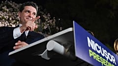 Кандидат в президенты Никусор Дан жестикулирует, обращаясь к сторонникам после закрытия избирательных участков на первом туре повторных президентских выборов в Бухаресте.