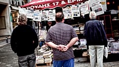 Έλληνες διαβάζουν τα πρωτοσέλιδα των εφημερίδων στην Αθήνα. 