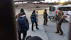 مهاجرون يتجهون إلى سيارة دورية الحدود بعد عبورهم غير القانوني وانتظارهم تقديم طلب اللجوء بين جدارين حدوديين يفصلان بين المكسيك والولايات المتحدة، يوم الثلاثاء، 21 يناير 2025، 