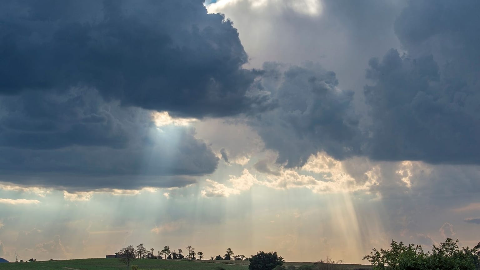 Un cielo nuvoloso con pioggia e raggi di sole.