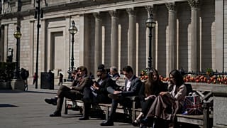 İnsanlar Londra'da The City olarak bilinen finans bölgesindeki İngiltere Merkez Bankası'nın önündeki banklarda oturuyor. 9 Nisan 2025.