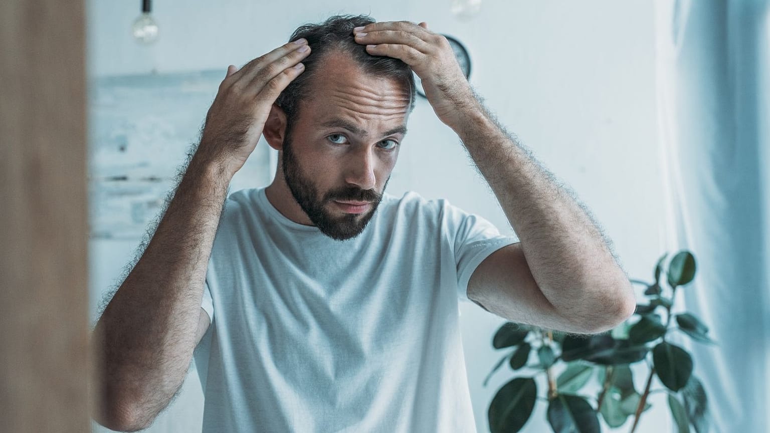 رجل أصلع يتفقد خط شعره.