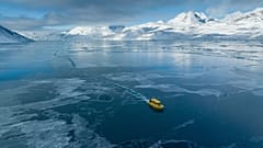 Grönland'ın Nuuk kenti dışında donmuş bir deniz girintisinden geçen bir tekne, 6 Mart 2025.