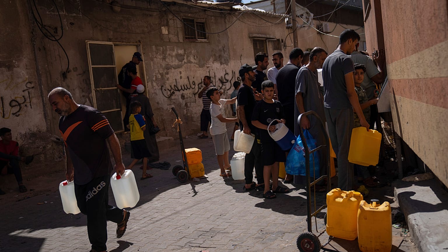  فلسطينيون يجمعون المياه من حنفية مياه، في ظل نقص مياه الشرب، في خان يونس، قطاع غزة، يوم الأحد 15 أكتوبر 2023.